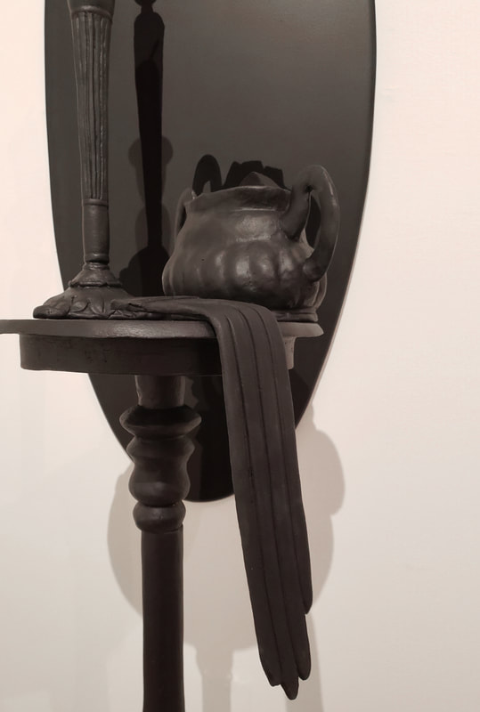 a stilllife made out of clay painted black with an extra black shadow. 